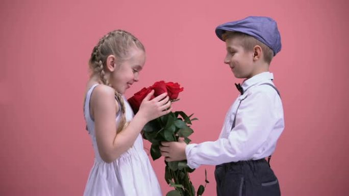 小绅士男孩在情人节向年轻女士赠送一束玫瑰花