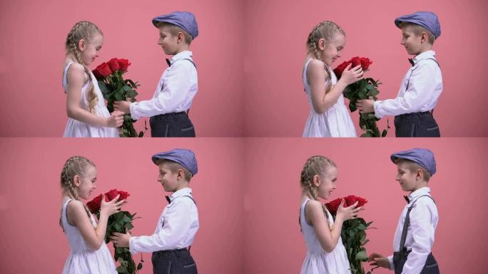 小绅士男孩在情人节向年轻女士赠送一束玫瑰花