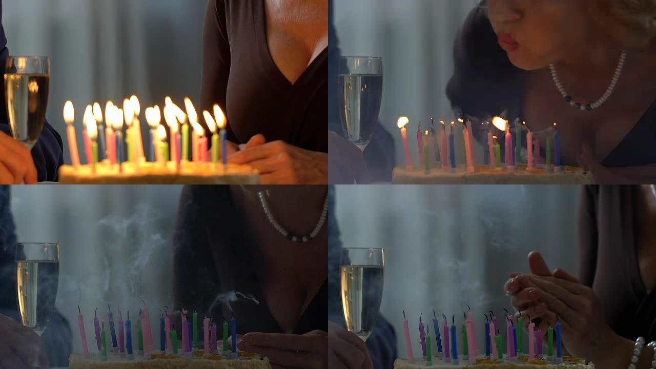 高级女士在蛋糕上吹蜡烛，与丈夫庆祝生日