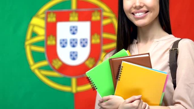 微笑的女性与笔记本葡萄牙国旗的背景，学生培训