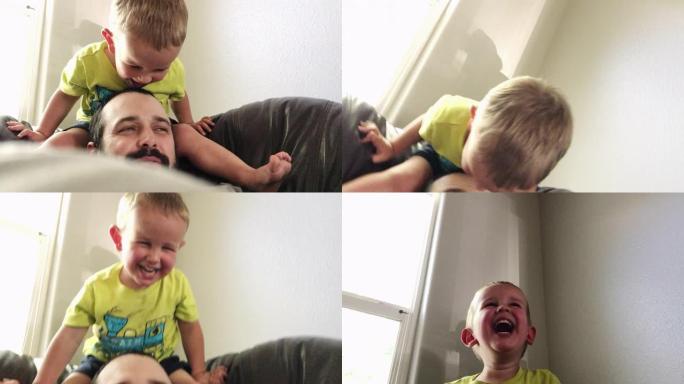一个三岁的高加索男孩坐在皮椅的靠背上，假装让他三十多岁的高加索父亲感到惊讶，因为他们俩都在室内大笑