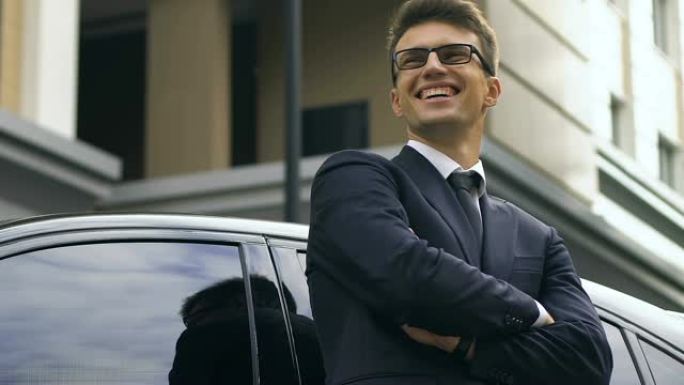自信的商人站在汽车旁，开心地微笑着，成功的交易
