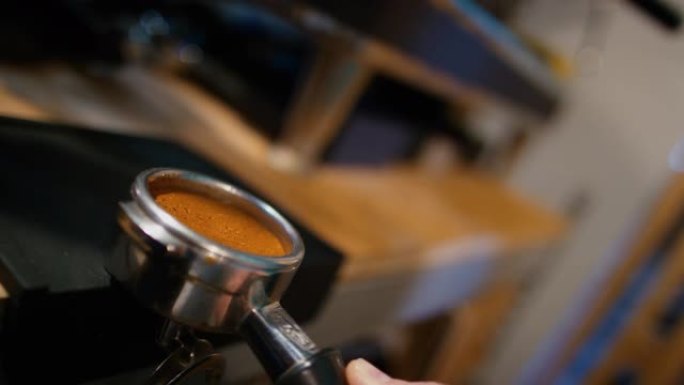 咖啡师在咖啡店里煮浓缩咖啡时，在Portafilter中放平和捣碎新鲜的咖啡渣