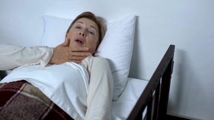 已退休的女病人躺在病床上感到哮喘发作并寻求帮助