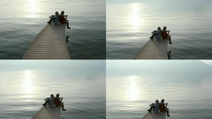 夫妇坐在那里享受大气湖码头欣赏宁静的山景