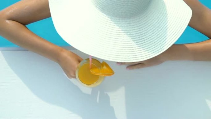 戴着大帽子的女人在豪华度假酒店泳池酒吧游泳和喝鸡尾酒