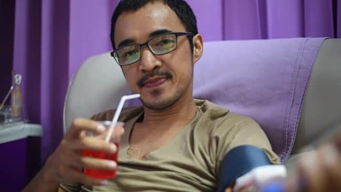 年轻人喝钙水，挤压球在他的手中的单个供体血小板血液在医院。