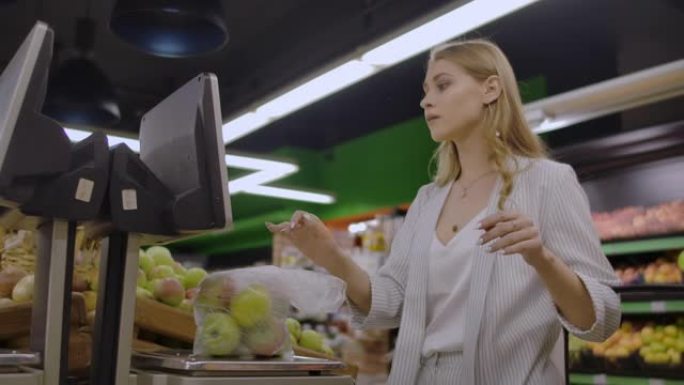 中年妇女在超市称一袋苹果。