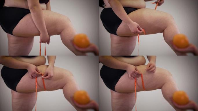 肥胖的高加索人无法辨认的女人用卷尺测量腿，因为女性的手在前景处拿着橙色。专注于背景。超重，肥胖，不健
