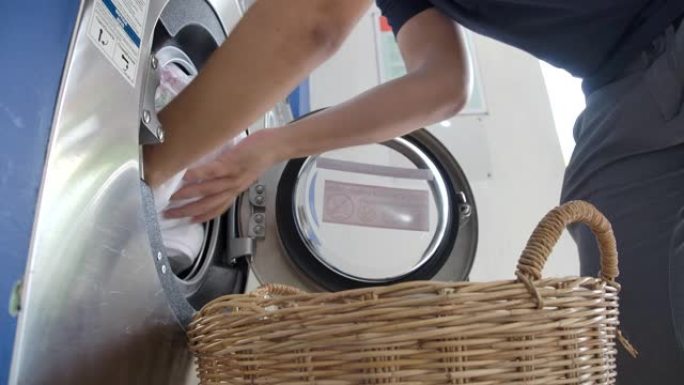 一个人洗衣服使用投币式洗衣机。