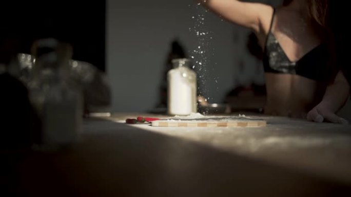 从裸体女人的手上倒在一块砧板上的面粉倒在厨房的木桌上。慢动作。