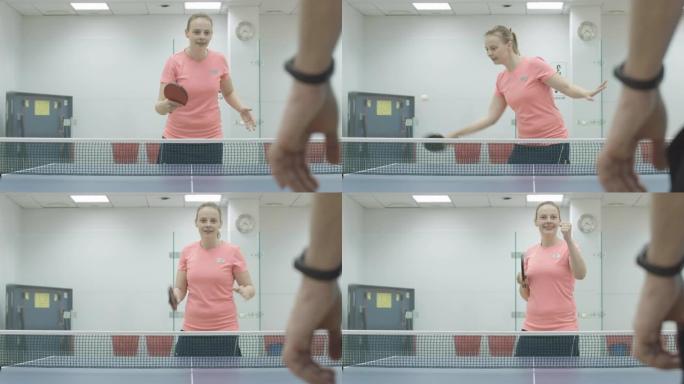 正面金发女运动员在乒乓球比赛中获胜的肖像。开朗微笑的年轻白人女子打乒乓球，在健身房做胜利手势。