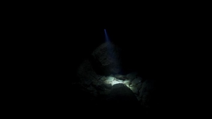 潜水潜水员的慢动作镜头，探索仅由头灯照亮的黑暗洞穴