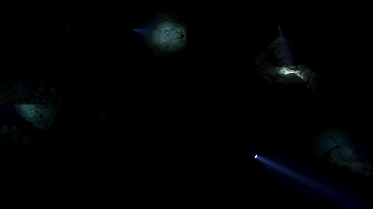 潜水潜水员的慢动作镜头，探索仅由头灯照亮的黑暗洞穴