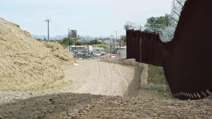 在晴朗，阳光明媚的日子里，在一条土路，美国海关和边境巡逻队以及墨西哥和美国之间的钢板条边境墙的拍摄中