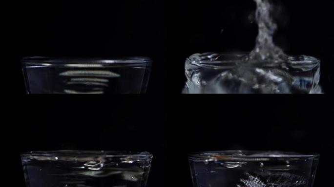 冰块落在装有水的玻璃杯中。黑色背景上的慢动作