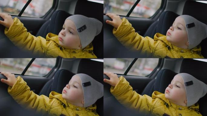 男孩看着车窗。和家人一起旅行。男婴看着窗外的汽车驾驶公路旅行。可爱的蹒跚学步的男孩坐在行驶中的汽车座