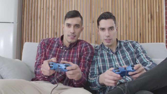 快乐的成年白人男子玩电子游戏的肖像。微笑的双胞胎兄弟在比赛中获胜。休闲，生活方式，幸福。