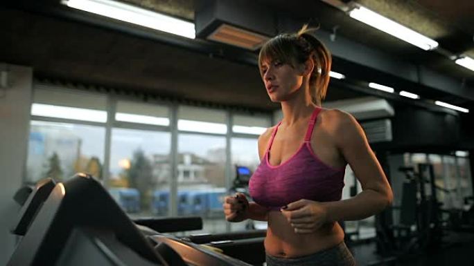 在健身房进行运动训练时，年轻的运动女子在跑步机上慢跑。慢动作。