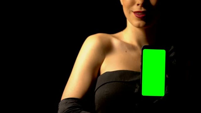 穿着优雅连衣裙的女人展示绿屏智能手机，在线赌场