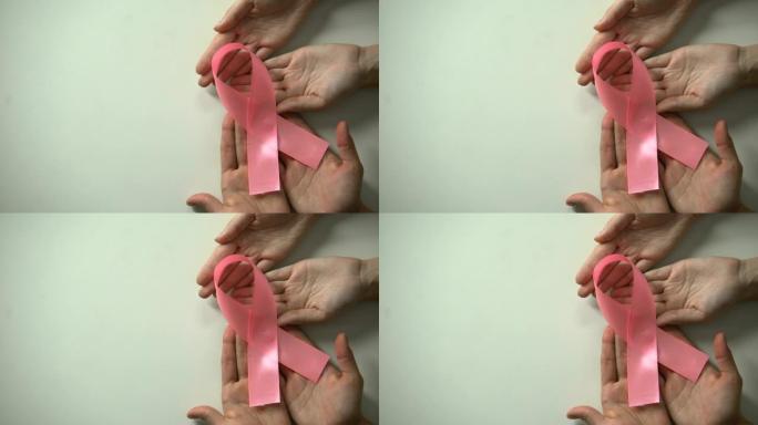 人们向镜头举起粉红丝带，发起预防乳腺癌运动
