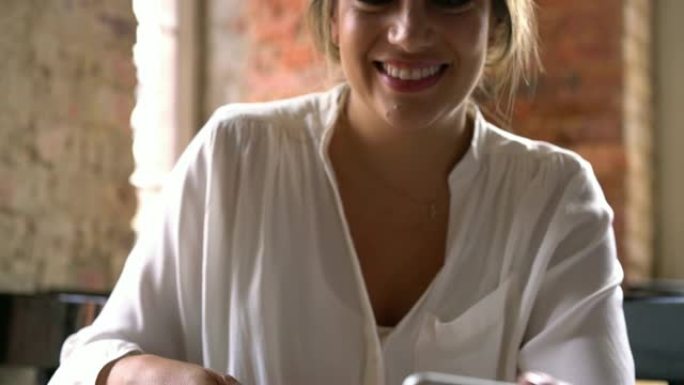 美女在面包店喝茶时在智能手机上聊天的特写镜头