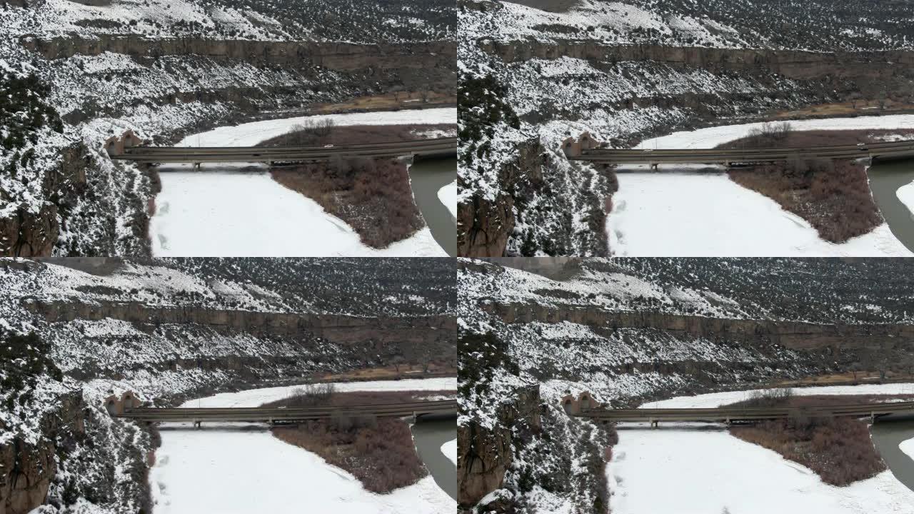 在一个白雪皑皑、阴云密布的冬日，在科罗拉多州落基山脉的70号州际公路上，行驶在科罗拉多河旁的70号州
