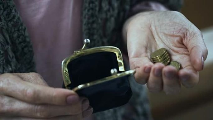 可怜的老妇遭受震颤，将硬币放在钱包中，是金融危机的受害者