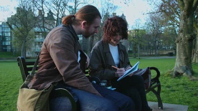 学生夫妇在公园长凳上做笔记