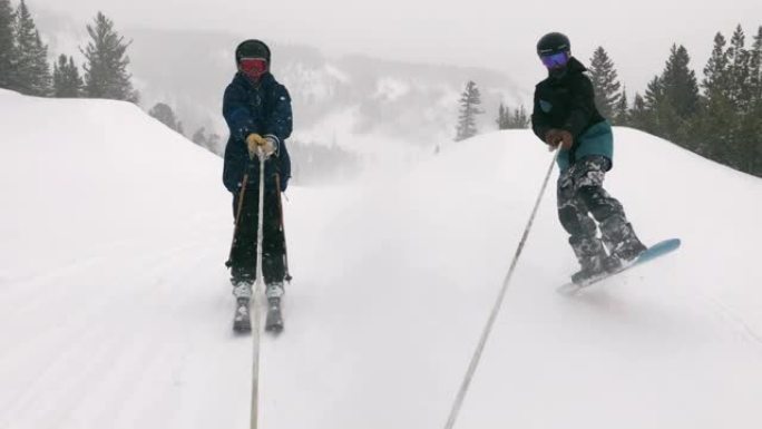 在下雪，阴天的冬天，在科罗拉多州博尔德附近的Eldora滑雪胜地，一名滑雪者和一名滑雪者被拉到雪地摩