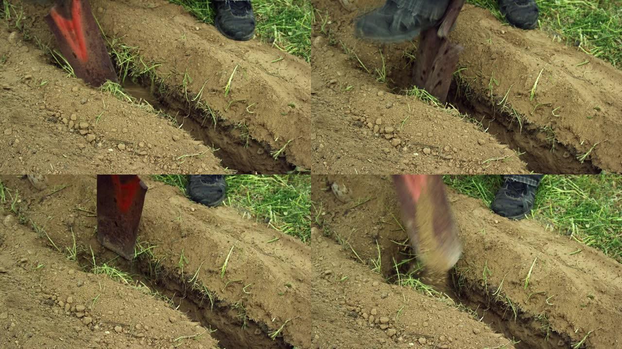 一名白人男子使用生锈的挖沟铲在地下挖了一条沟，然后弯下腰清除洞中的污垢