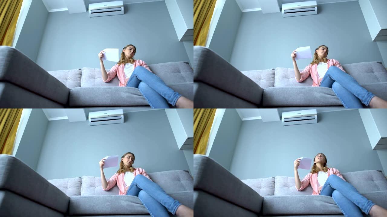 女人坐在沙发上挥舞着纸，受热，空调故障