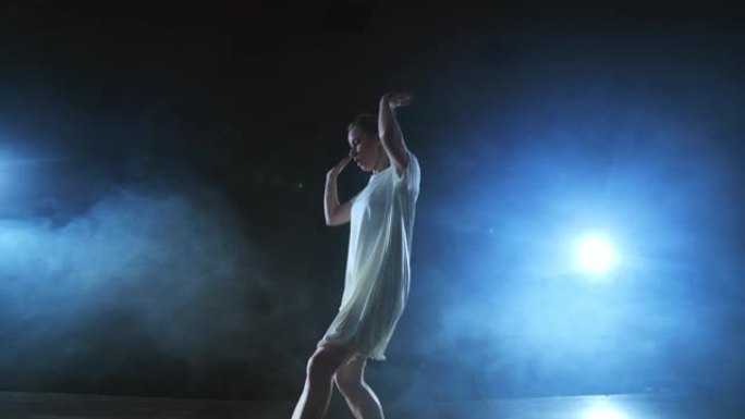 变焦相机用软件和烟雾在舞台上移动。女芭蕾舞演员穿着白色连衣裙跳舞，旋转塑料，同时表演旋转和旋转，体验