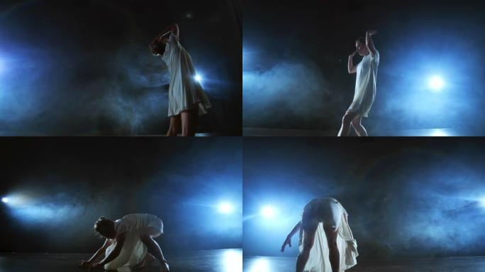 变焦相机用软件和烟雾在舞台上移动。女芭蕾舞演员穿着白色连衣裙跳舞，旋转塑料，同时表演旋转和旋转，体验