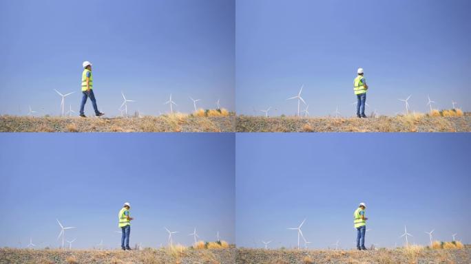 使用智能手机在风力涡轮机农场工作的男性工程师