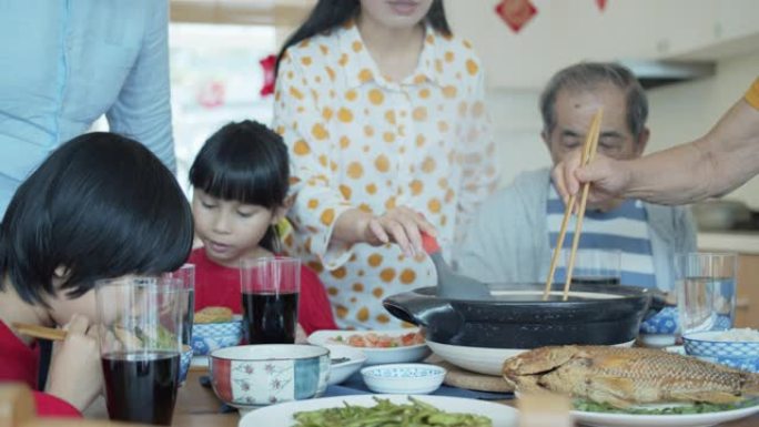 三代家庭把食物放在桌子上，在春节吃饭