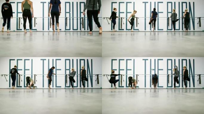 一个由五个二十多岁的妇女组成的多种族团体走到芭蕾舞鞋前，开始在健身室里伸展运动
