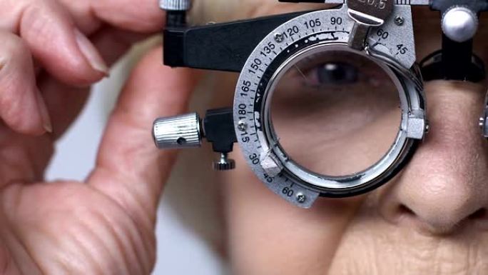 老妇人脱下带镜片的光学试验架，视力模糊，老花眼