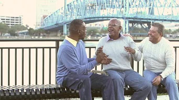 三名多种族的高级男子在公园长椅上交谈