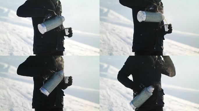 Man pours tea from a thermos winter