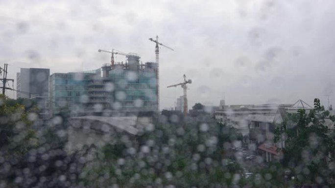 4K: 窗玻璃上的雨滴，背景中的起重机建筑物
