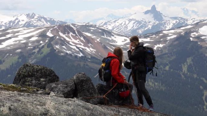 女攀岩者讨论路线，在岩石山顶上准备装备