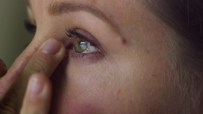 一位三十多岁的白人妇女用手指在眼睛下化妆