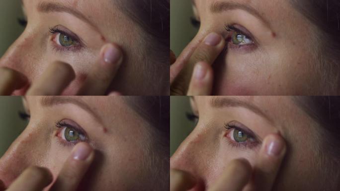 一位三十多岁的白人妇女用手指在眼睛下化妆