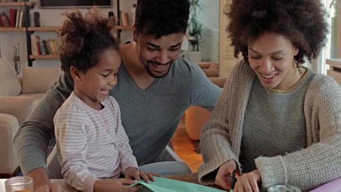 快乐的非裔美国人家庭在用纸和剪刀制作创意的同时玩得开心。