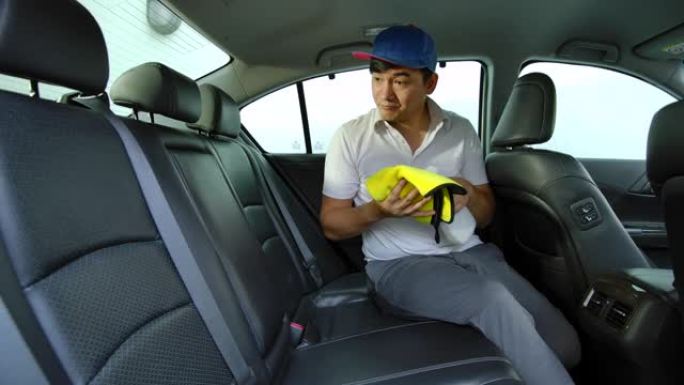亚洲男子正在汽车细节店清洁顾客汽车的内部。