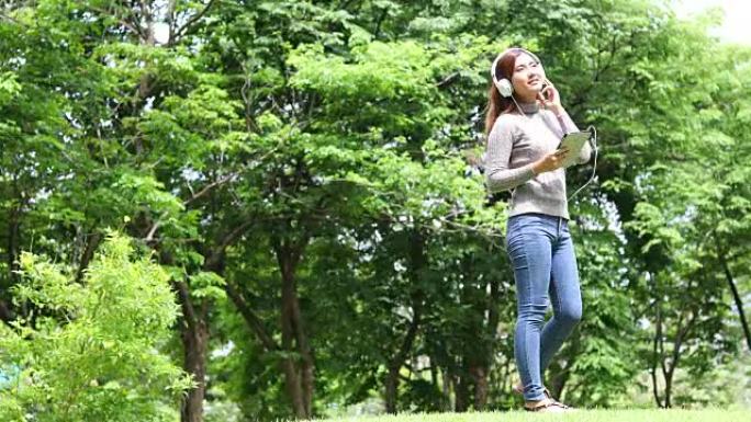 亚洲女人在公园里听音乐放松
