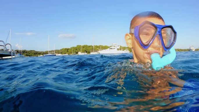 在海边阳光明媚的日子里，小男孩在水中玩潜水面具