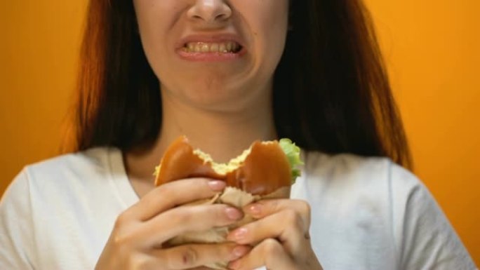 女人咬不开胃的汉堡，对食物质量不满，特写
