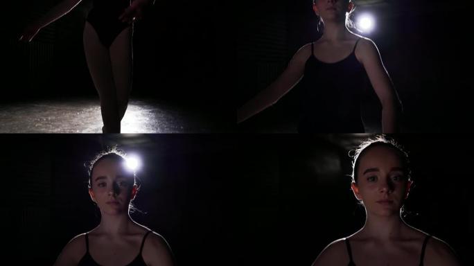 年轻的芭蕾舞演员站在工作室黑色背景上的聚光灯下。芭蕾舞女演员展示经典芭蕾舞剧。慢动作。